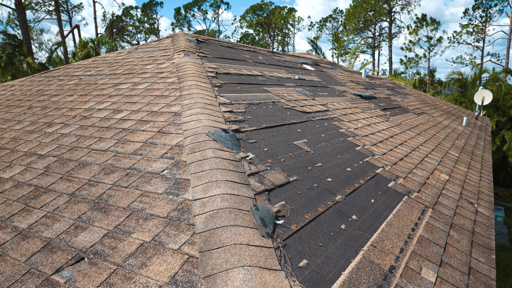 Roof with damaged shingles exposing underlying material, highlighting the need for repair.