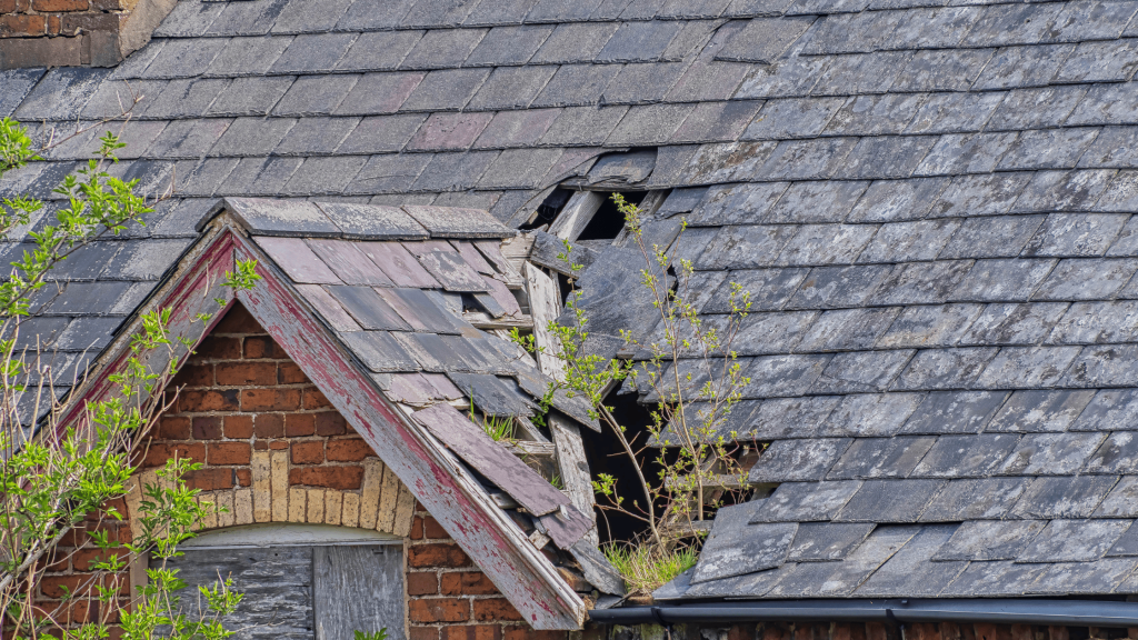 Severely damaged roof with missing shingles and visible structural issues, showcasing the need for professional roof repair after a storm, serviced by Black Bear Roofing.