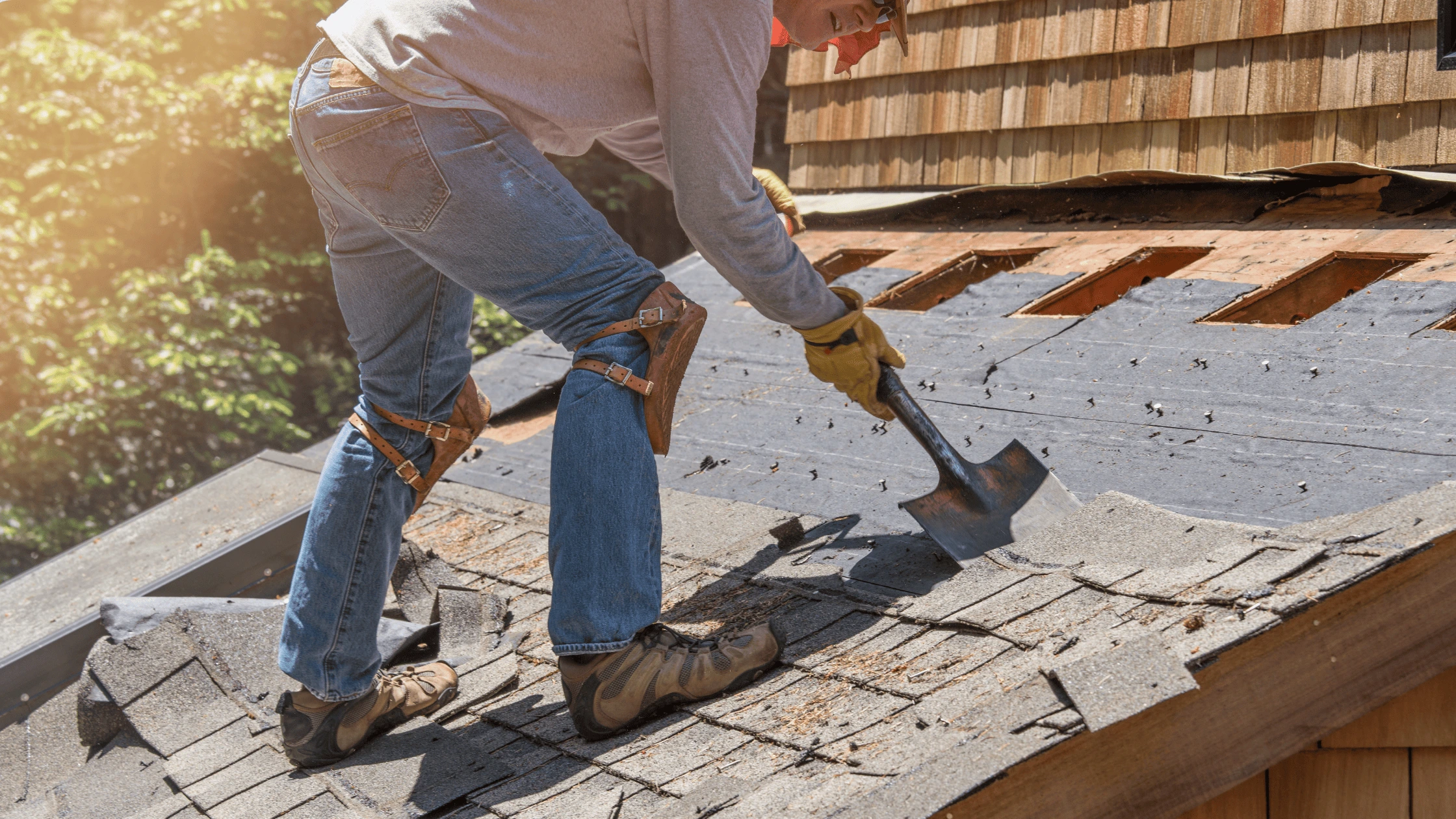 Roofing contractor removing old shingles during a reroofing project in Asheville, NC—part of a full roof replacement process.