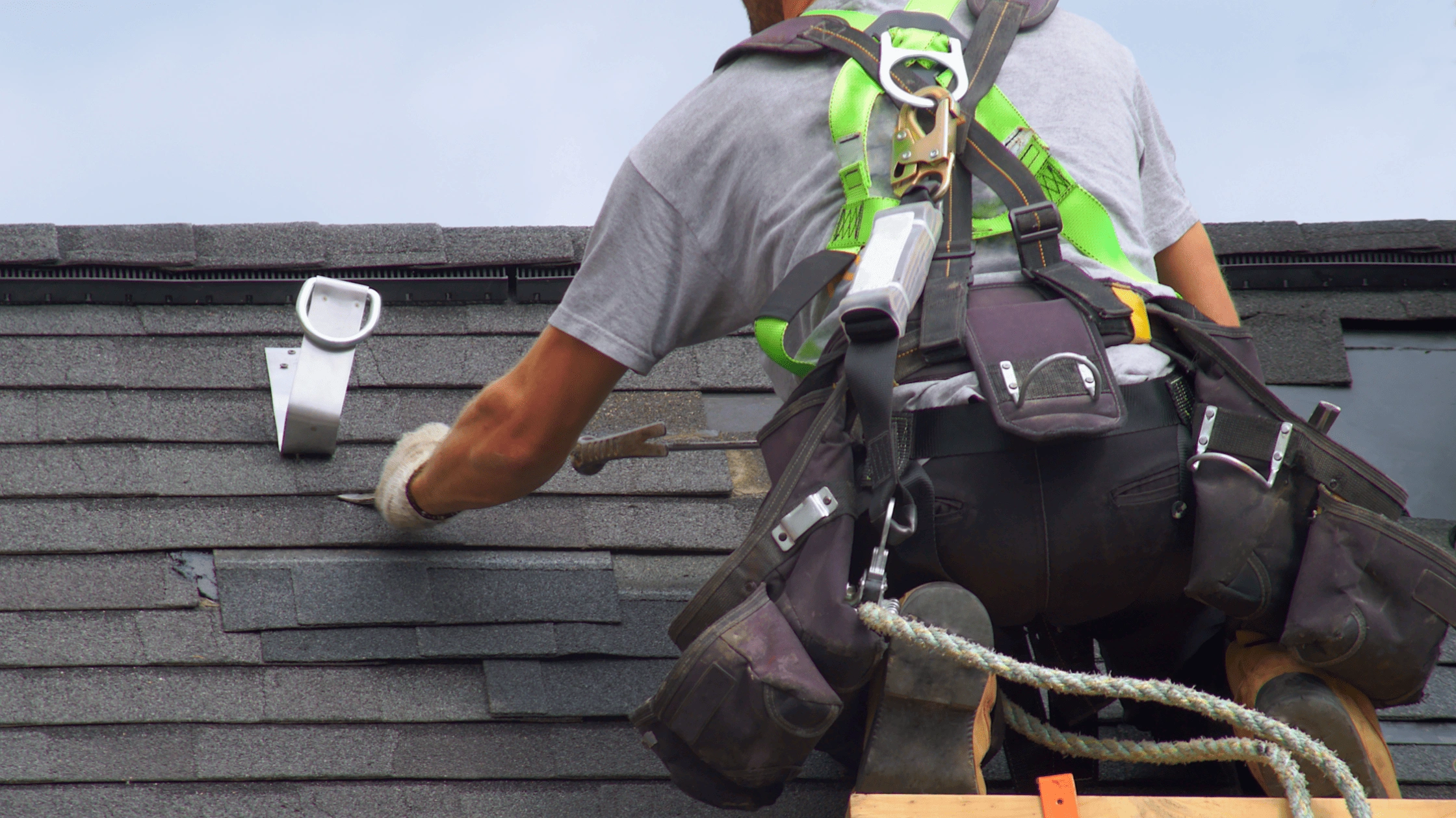 Professional roofer installing asphalt shingles on a home roof, representing roofing cost factors in Asheville, NC.